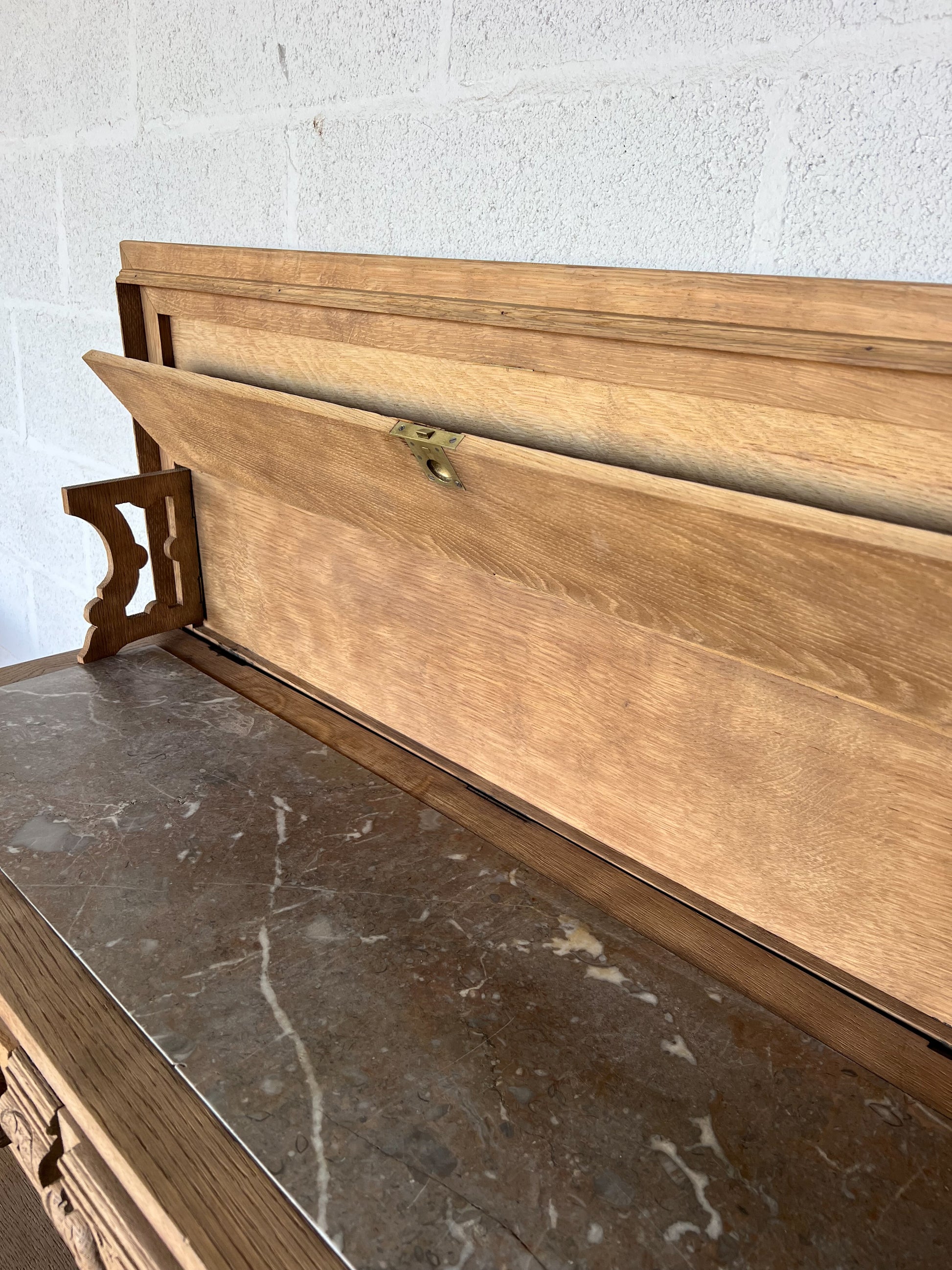 Console en chêne, le plateau se soulève pour laisser place à une tablette en marbre (fendue d'un coté) et à une petite étagère. Idéal en vanity dans une salle de bain, en console dans une entrée ou dans un salon, le compartiment au milieu sert à fermer les tiroirs mais la clé n'est pas présente.