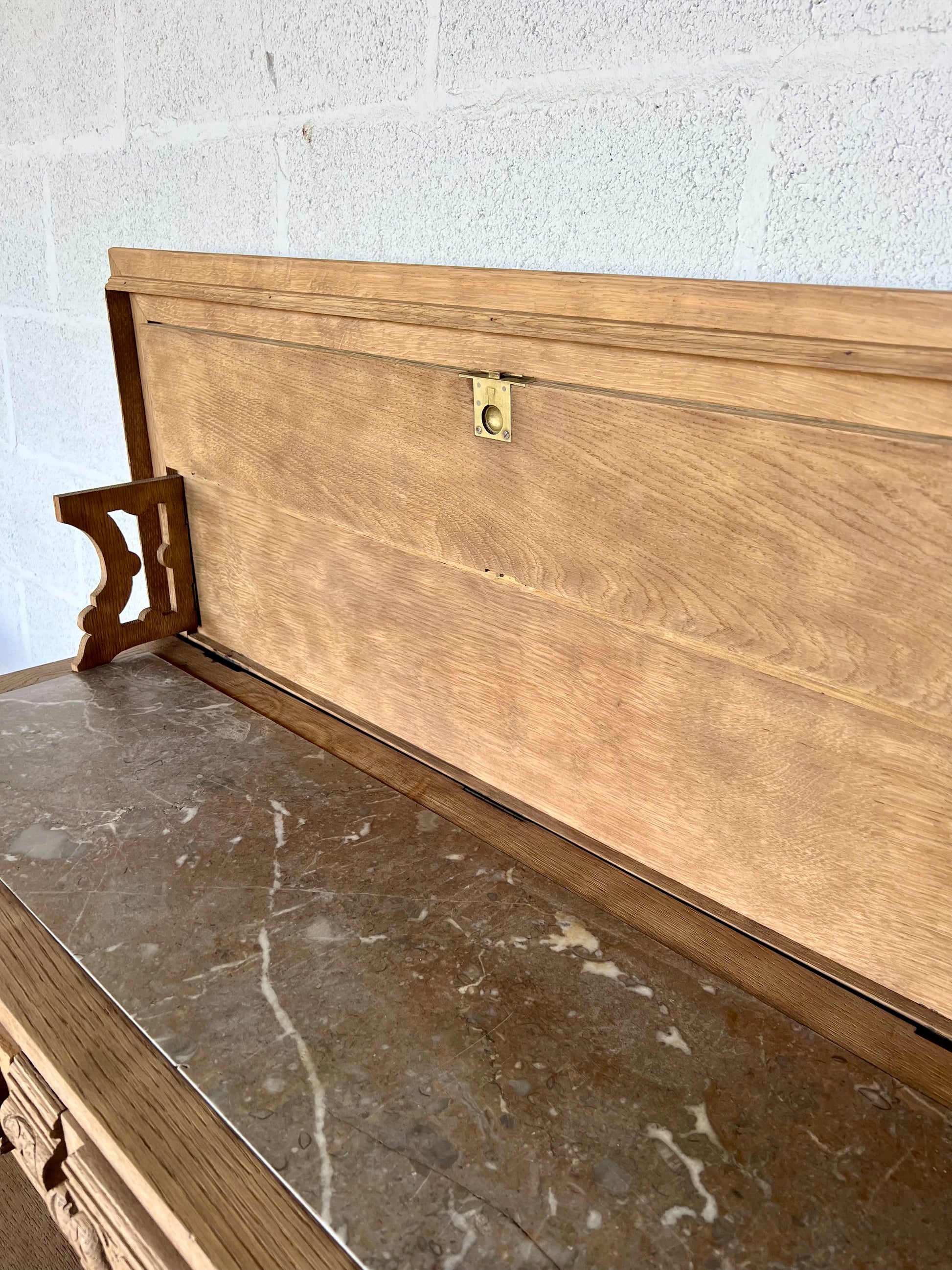 Console en chêne, le plateau se soulève pour laisser place à une tablette en marbre (fendue d'un coté) et à une petite étagère. Idéal en vanity dans une salle de bain, en console dans une entrée ou dans un salon, le compartiment au milieu sert à fermer les tiroirs mais la clé n'est pas présente.