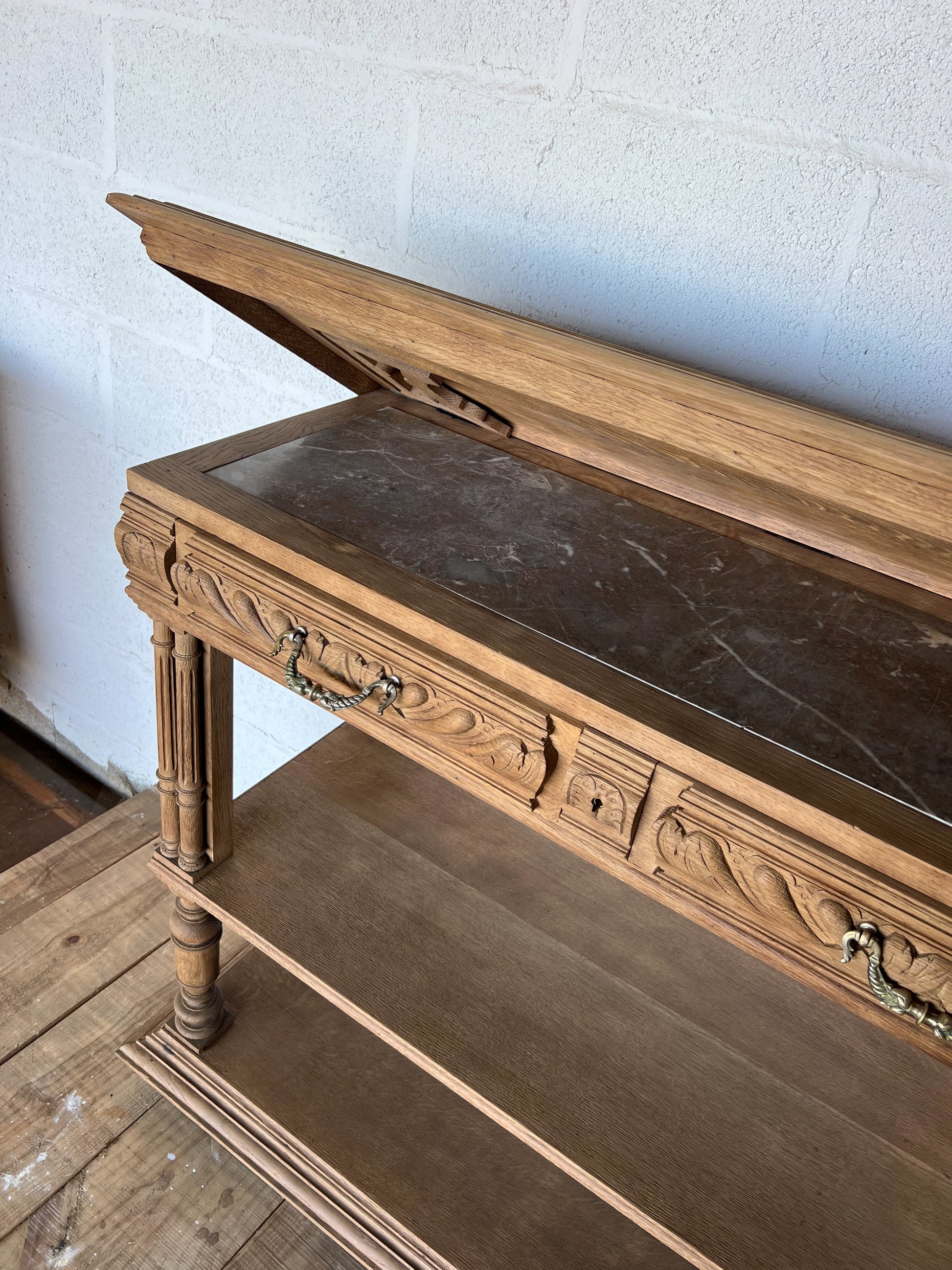 Console en chêne, le plateau se soulève pour laisser place à une tablette en marbre (fendue d'un coté) et à une petite étagère. Idéal en vanity dans une salle de bain, en console dans une entrée ou dans un salon, le compartiment au milieu sert à fermer les tiroirs mais la clé n'est pas présente.