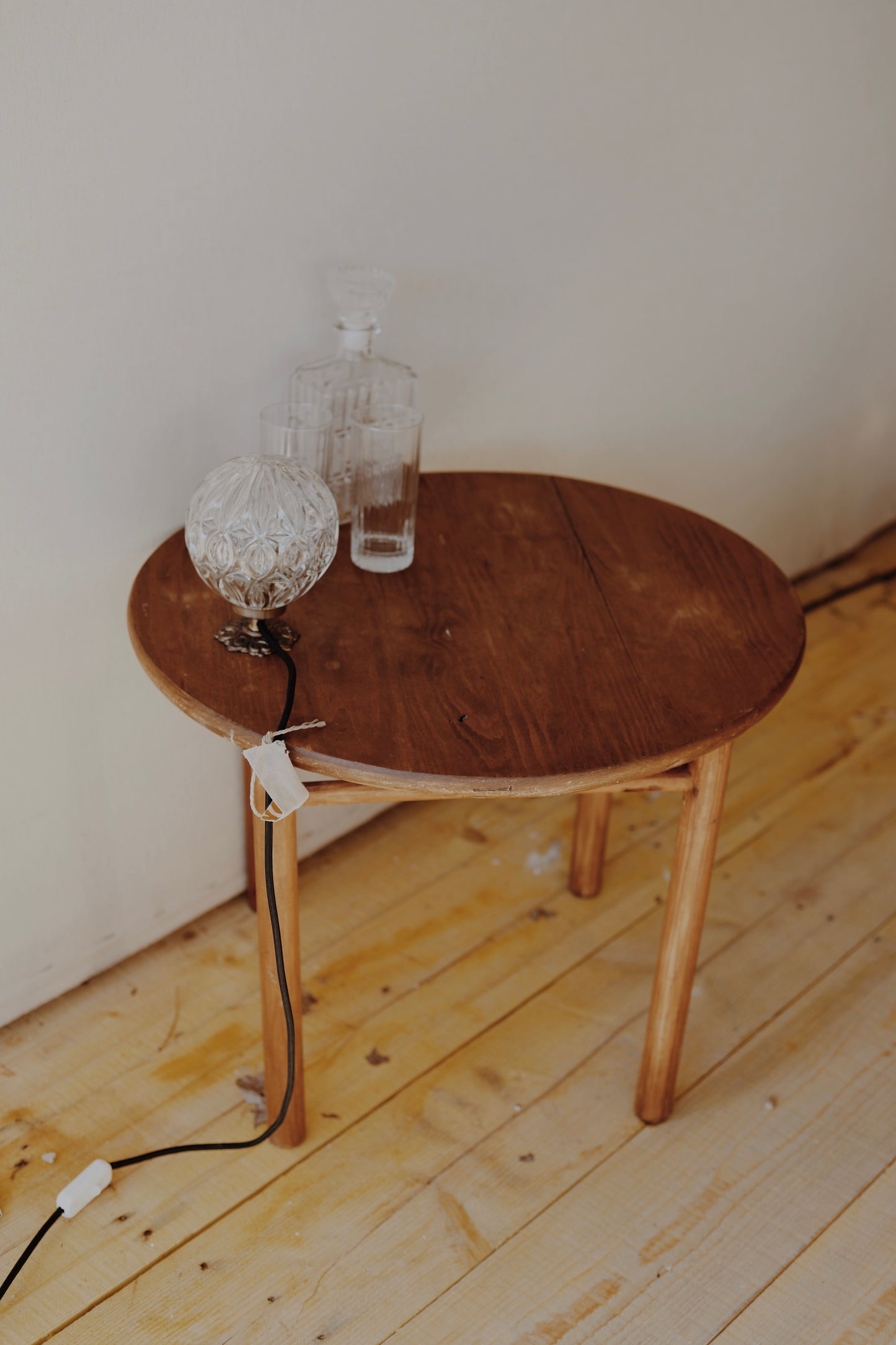 Table basse en bois ronde, teintée et protégée, une pièce originale avec une barre en dessous et un plateau légèrement incurvée au milieu, pas parfaitement plat.