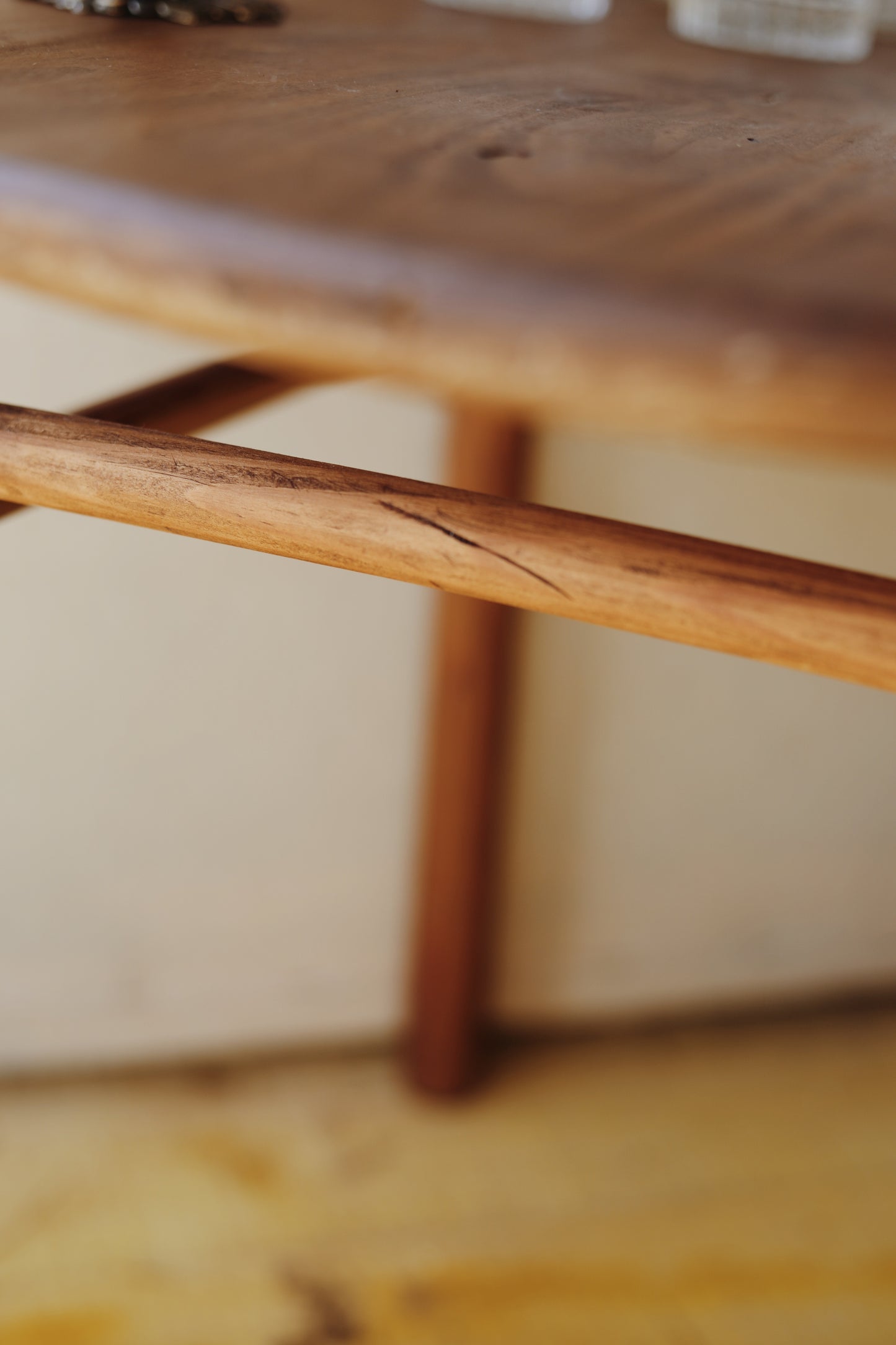 Table basse en bois ronde, teintée et protégée, une pièce originale avec une barre en dessous et un plateau légèrement incurvée au milieu, pas parfaitement plat.