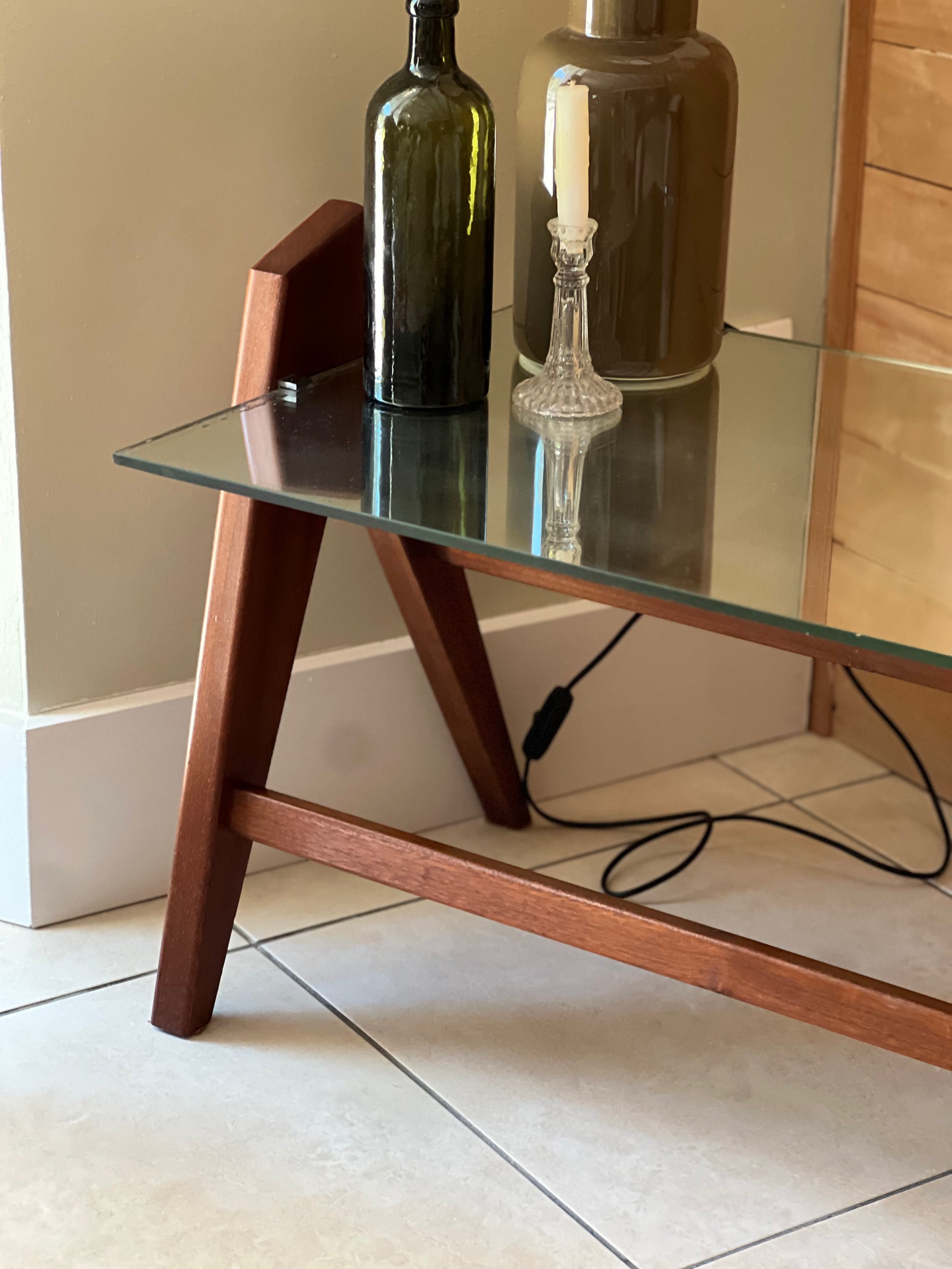 Table basse années 60, plateau en miroir, piqué sur les bords, piétement en bois.